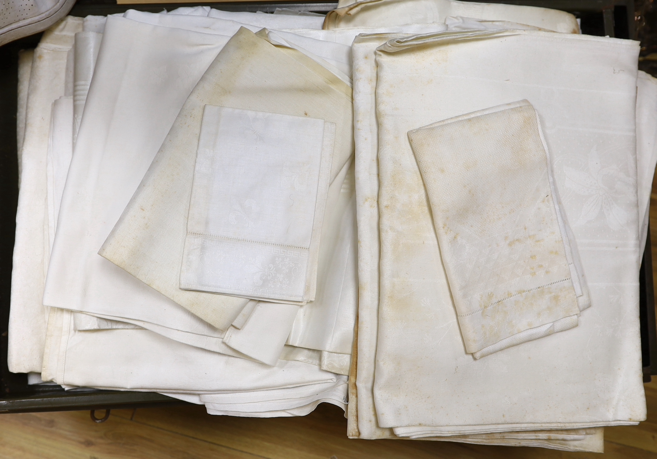 A tin trunk containing a large quantity of 19th and 20th century linen damask table cloths, together with a smaller quantity of linen sheets, trunk 86cm wide, 51cm deep, 31cm high